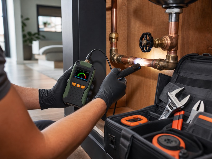 Plumber inspecting a copper pipe connection with diagnostic tools